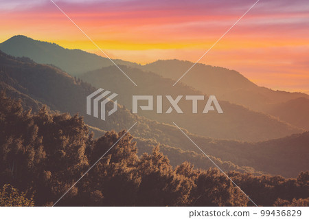 Toned landscape with layered summer mountains in evening haze at sunset in central Asia 99436829