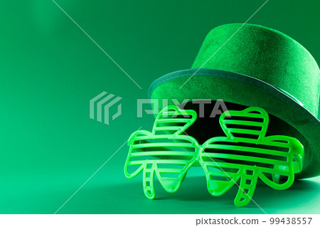 Image of green hat, green clover glasses and copy space on green background 99438557