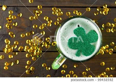 Image of beer glass, clover and gold confetti on wooden background Image of beer glass, clover and gold confetti on wooden background 99438592
