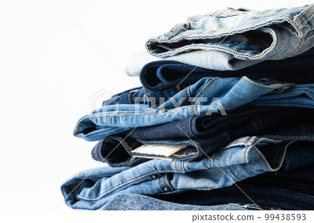 Diverse folded jeans lying in stack with copy space on white background Diverse folded jeans lying in stack with copy space on white background 99438593