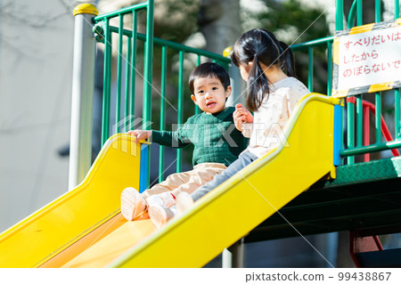 Children holding hands and sliding down a slide Children holding hands and sliding down a slide 99438867