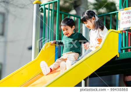 Children holding hands and sliding down a slide Children holding hands and sliding down a slide 99438868