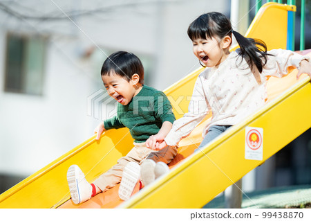Children holding hands and sliding down a slide Children holding hands and sliding down a slide 99438870