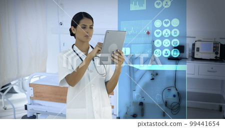 Composition of biracial female doctor using tablet over digital interface and room in hospital 99441654