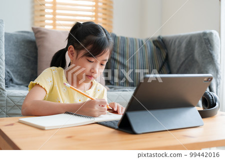 Asian little girl doing homework, learning, student using digital tablet. Asian little girl doing homework, learning, student using digital tablet. 99442016