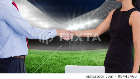 Composition of businessman and businesswoman shaking hands over sports stadium 99443460