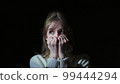 The girl covers her face with her hands in fear 99444294
