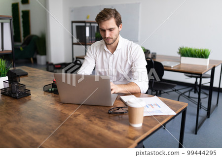 young businessman man in a white shirt works on laptops in the office 99444295