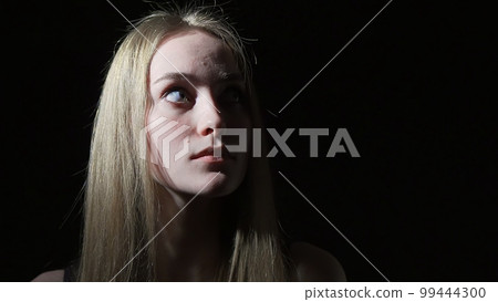 The young woman shows emotions of fear on her face The young woman shows emotions of fear on her face 99444300
