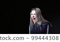 Young woman screaming on black background 99444308