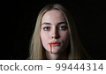 A young woman pours blood from her mouth close-up 99444314