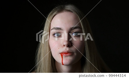 A young woman pours blood from her mouth close-up A young woman pours blood from her mouth close-up 99444314