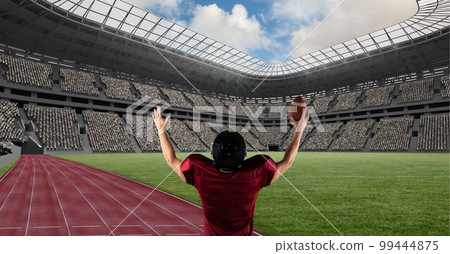 Composition of male american football player holding ball and raising hands over sports stadium 99444875