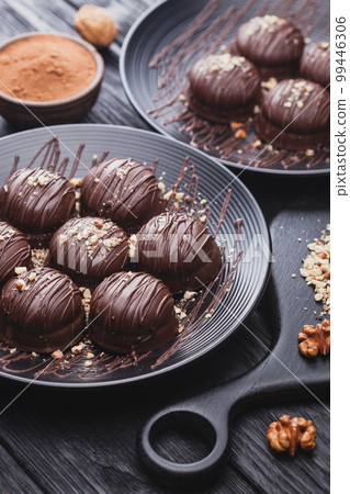 delicious mini chocolate cakes with walnut on a black wooden table delicious mini chocolate cakes with walnut on a black wooden table 99446306