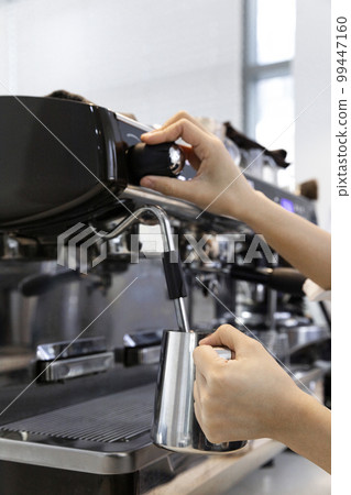 barista steaming milk for cafe latte in cafe 99447160