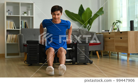 Full length of male athlete exercising on sports bench at home. Home fitness and healthy lifestyle concept 99447906