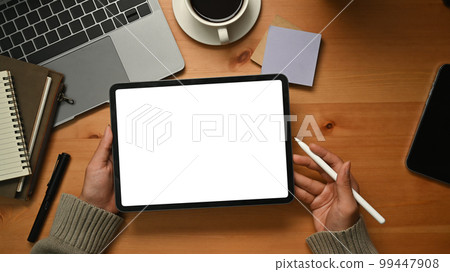 Creative woman hands holding digital tablet with white empty display over wooden working desk 99447908