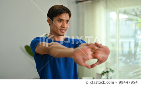 Athletic young asian man stretching arms before home workout. Healthy lifestyle, sport and motivation concept 99447954