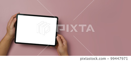 Above view of man hands holding digital tablet with empty display over pink background. Copy space for your text 99447971