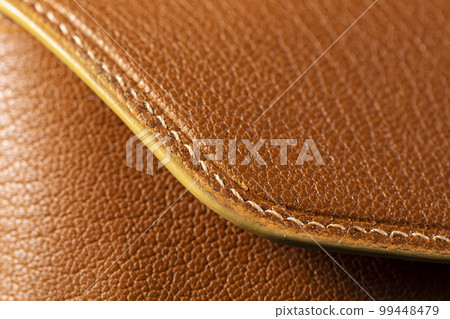 Part of a brown leather wallet or case with stitching. 99448479