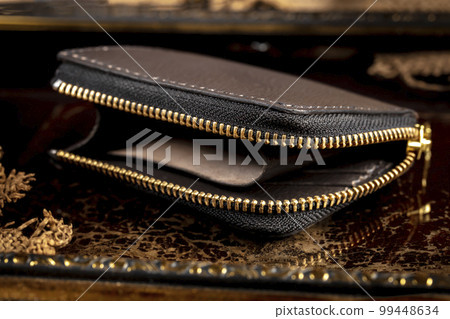 Leather wallet with a golden zipper close-up on a dark background. 99448634