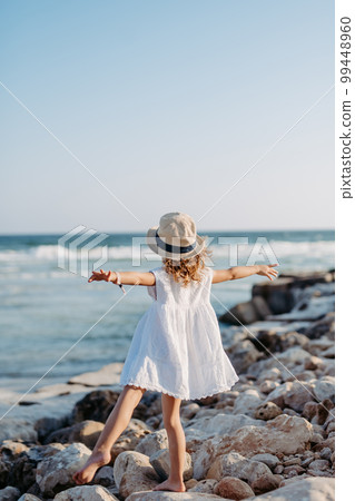 Rear view of little girl looking at the sea. 99448960