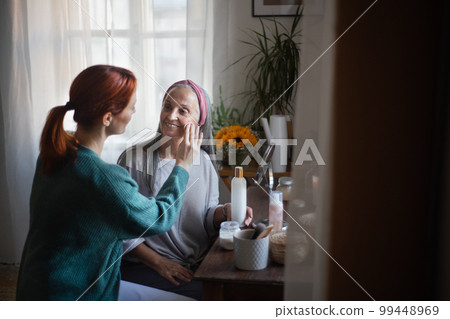 Caregiver helping her client with a make up. 99448969
