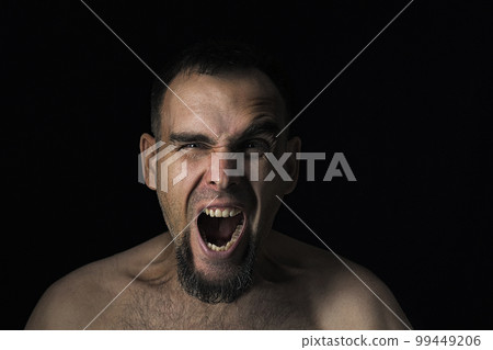 Close-up of a young, angry, disgruntled man looking into the camera and shouting. Caucasian angry man shouting directly at the camera. An angry man. Stress hysterical. Emotional portrait. Close-up of a young, angry, disgruntled man looking into the camera and shouting. Caucasian angry man shouting directly at the camera. An angry man. Stress hysterical. Emotional portrait. 99449206