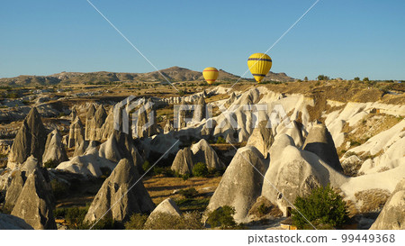 Two yellow balloons in front of the Valley of Love in Cappadocia. Beautiful morning view from hot air balloons. A popular tourist spot in Turkey. Two yellow balloons in front of the Valley of Love in Cappadocia. Beautiful morning view from hot air balloons. A popular tourist spot in Turkey. 99449368