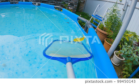 The mesh skimmer removes leaves from the surface of the backyard pool water. Maintain and care for your home swimming pool with the mesh skimmer. First-person view. The mesh skimmer removes leaves from the surface of the backyard pool water. Maintain and care for your home swimming pool with the mesh skimmer. First-person view. 99450143