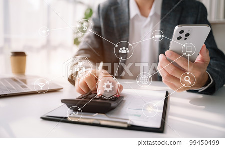 Male businessman working on desk office with using a calculator to calculate the numbers and business report talk smart phone on office desk, finance accounting concept. 99450499