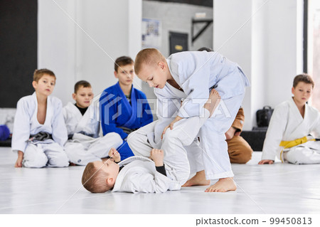 Little boys, children in white kimono training judo, jiu-jitsu indoors. Professional sports club for kids 99450813