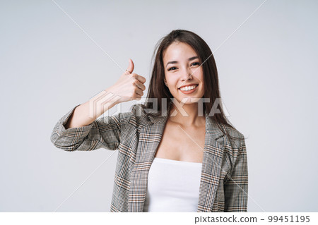 Young happy asian woman with long hair in suit on grey background Young happy asian woman with long hair in suit on grey background 99451195