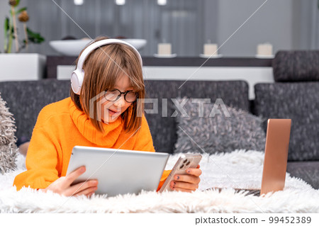 children and modern technology. play and study at home using a laptop, tablet, smartphone and wireless headphones 99452389