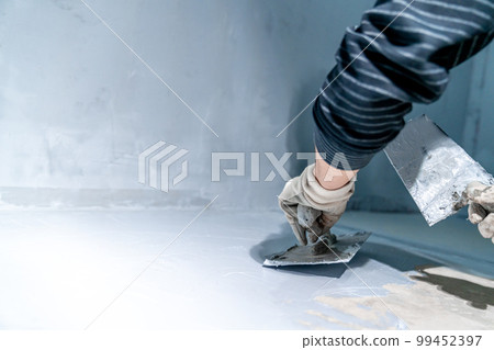 work with trowel on floor and wall in new room in building work with trowel on floor and wall in new room in building 99452397