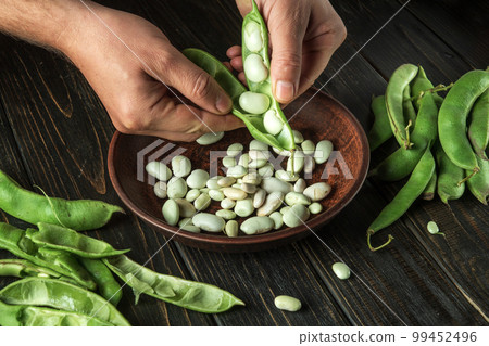 Cook hands while working in the kitchen. The chef separates the beans from the green pods Cook hands while working in the kitchen. The chef separates the beans from the green pods 99452496