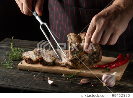 Grilled juicy beef steak, selected marbled meat sliced on a black background of a wooden table with a fork in the chef hand Grilled juicy beef steak, selected marbled meat sliced on a black background of a wooden table with a fork in the chef hand 99452530