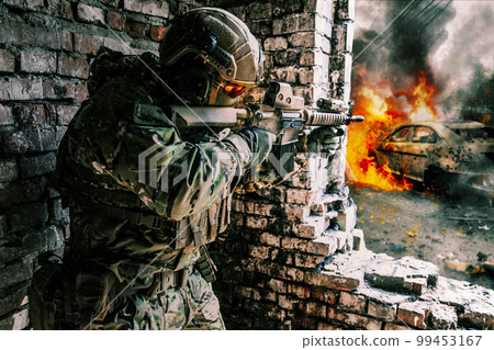 A soldier in action in a ruined building, danger of modern warfare. Fighting in destroyed building, engaged in combat with an unseen enemy. Armed with a firearm and other equipment. Concept of urban 99453167