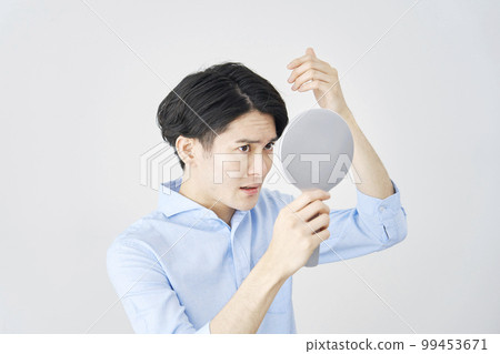 A man worried about looking at his hair in the mirror White background A man worried about looking at his hair in the mirror White background 99453671