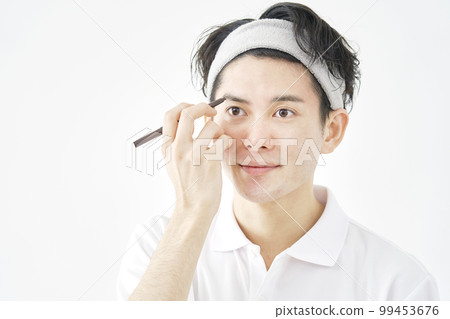 A man drawing eyebrows with an eyebrow pencil White background A man drawing eyebrows with an eyebrow pencil White background 99453676