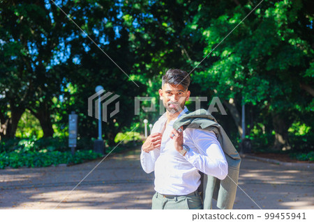 Indian businessman smiling with his suit jacket over his shoulder Indian businessman smiling with his suit jacket over his shoulder 99455941