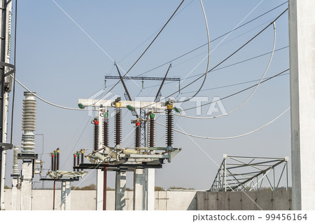 Part of high-voltage substation on blue sky background with switches and disconnectors. Ukrainian energy infrastructure. Part of high-voltage substation on blue sky background with switches and disconnectors. Ukrainian energy infrastructure. 99456164