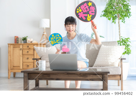 Oshikatsu A girl from the z generation who cheers for her favorite by waving a fan while watching a live video 99456402