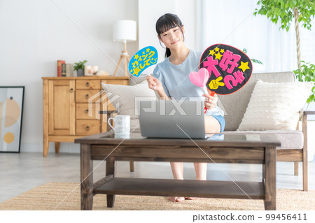 Oshikatsu A girl from the z generation who cheers for her favorite by waving a fan while watching a live video 99456411