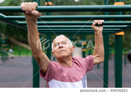 Old climbing on horizontal ladder outdoors Old climbing on horizontal ladder outdoors 99456801