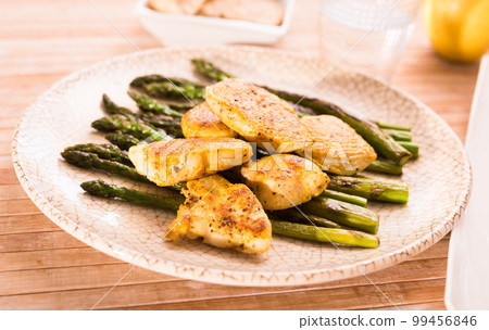 cooked dish. Chicken nuggets with green asparagus on plate 99456846
