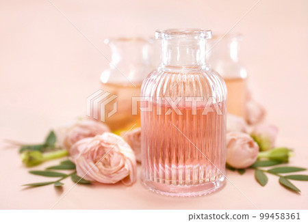 Colorful essential oil bottles on pink rose background, selective focus, shallow DOF, toned Colorful essential oil bottles on pink rose background, selective focus, shallow DOF, toned 99458361