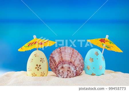 Happy easter. Yellow and blue eggs with conch shell under umbrellas on sandy beach of the sea or ocean. Holiday postcard in hot country. Travel, spring, summer. Copy space Happy easter. Yellow and blue eggs with conch shell under umbrellas on sandy beach of the sea or ocean. Holiday postcard in hot country. Travel, spring, summer. Copy space 99458773