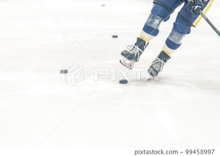 hockey puck on the ice of the winter stadium. skates of a hockey player during training hockey puck on the ice of the winter stadium. skates of a hockey player during training 99458997