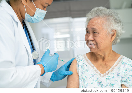 Elderly Asian woman wearing face mask getting covid19 or coronavirus vaccine by doctor make injection. Elderly Asian woman wearing face mask getting covid19 or coronavirus vaccine by doctor make injection. 99459349